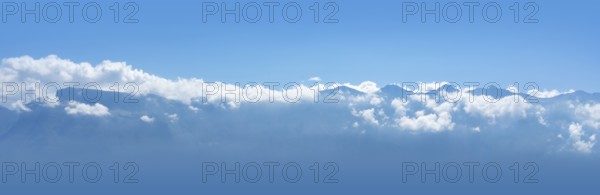 Sunny alpine mountain scenery showing a mountain range and clouds in front of blue sky