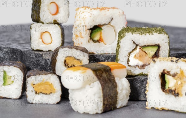 Various sushi dishes on dark grey stone surface