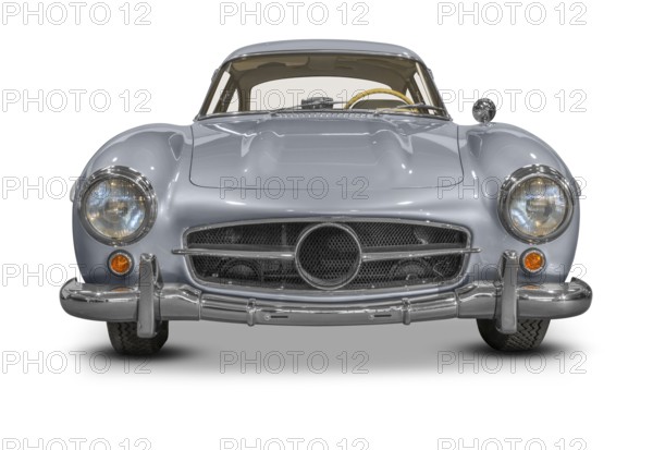 Frontal shot of a silver colored historic vehicle coupe in white back with shadow