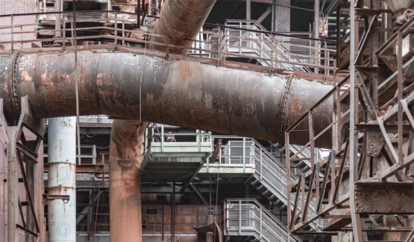 Weathered rundown industrial scenery with old corroded steel girders, stairs and metal tubes