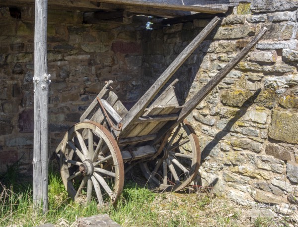 Medieval wooden cart at a stone wall in sunny ambiance