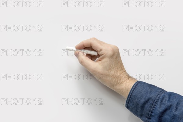 Male hand with white crayon in light back