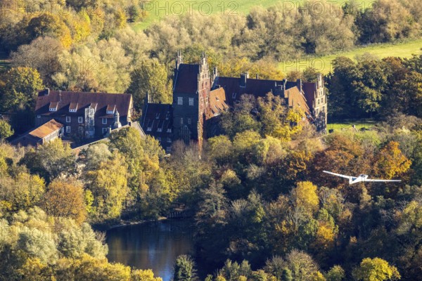 Aerial photo, motor glider at Heessen Castle in the autumnal forest in the Heessen district of Hamm, Ruhr area, North Rhine-Westphalia, Germany, education, educational institution, castle, DE, Europe, aircraft, Hamm, autumn colours, educational institute, aerial photo, aerial photography, aerial photography, motor glider, castle, castle complex, school, overview, bird's-eye view, overview