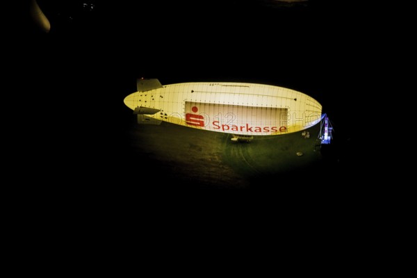 Aerial photograph, Sparkasse airship, airfield Essen Mülheim, Haarzopf, Essen, Ruhr area, North Rhine-Westphalia, Germany, outdoor lighting, DE, twilight, Europe, flying objects, light pollution, aerial photograph, aerial photography, aviation, aerial photography, airship, Mülheim an der Ruhr, night aerial photograph, streetlights, street lamps, overview, bird's eye view, zeppelin, illuminated, illuminated houses, illuminated house, birds-eyes view, artificial light, night, nightflight, overview