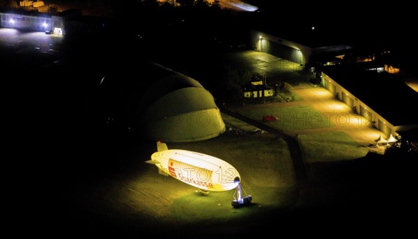 Aerial photograph, Sparkasse airship, airfield Essen Mülheim, Haarzopf, Essen, Ruhr area, North Rhine-Westphalia, Germany, outdoor lighting, DE, twilight, Europe, flying objects, light pollution, aerial photograph, aerial photography, aviation, aerial photography, airship, night aerial photograph, streetlights, street lamps, overview, bird's eye view, zeppelin, illuminated, illuminated houses, illuminated house, birds-eyes view, artificial light, night, nightflight, overview