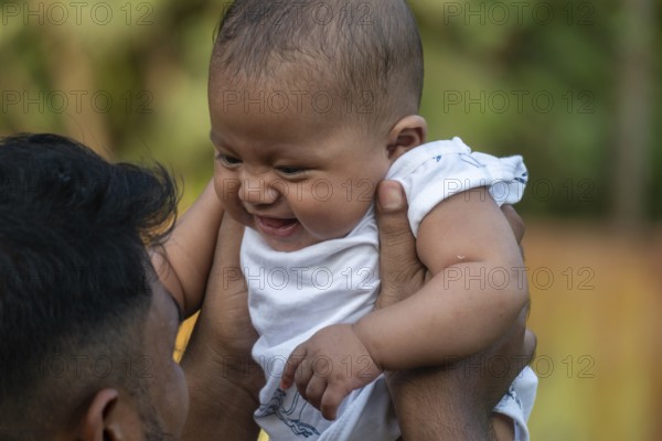 Baby laughing joyfully as they are lifted up outdoors-Dhaka, Bangladesh
