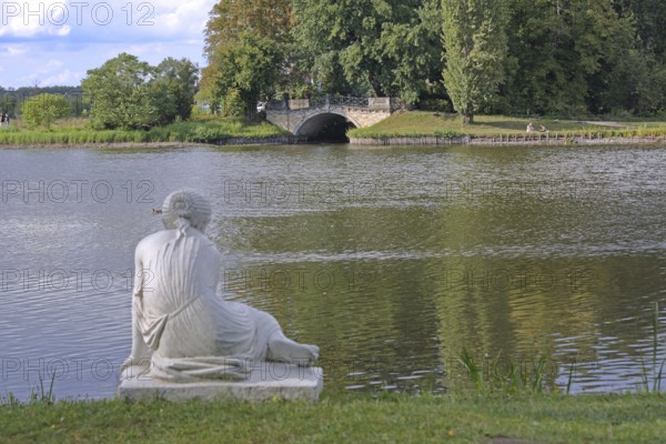 Female shell collector on the shore of Lake Wörlitz and Wolf Bridge, female shell collector, white lying, sitting female figure, stone sculpture, artwork, landscape park, UNESCO, landscape park, Dessau-Wörlitz Garden Kingdom, Wörlitz, Saxony-Anhalt, Germany