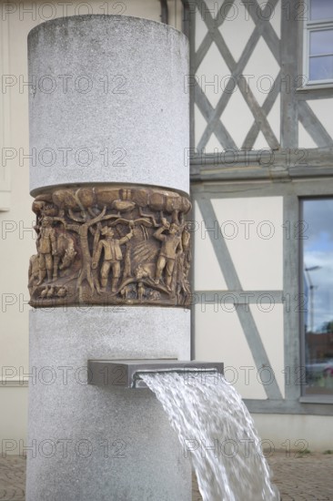 Market fountain with relief on the town's history, water jet, market square, Haldensleben, Saxony-Anhalt, Germany