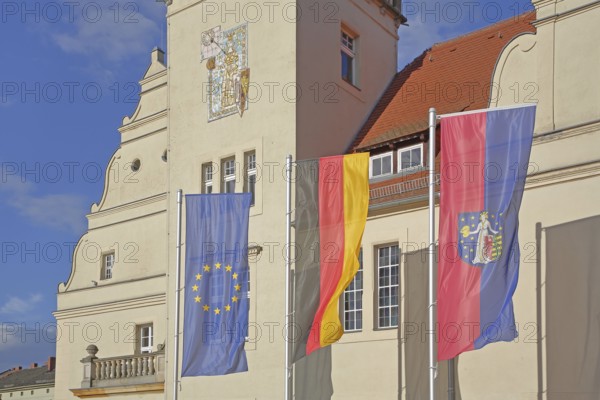 Renaissance town hall with EU flag, German national flag and town flag, three, flags, sundial, wall mosaic, town coat of arms, Coswig, Fläming, Saxony-Anhalt, Germany