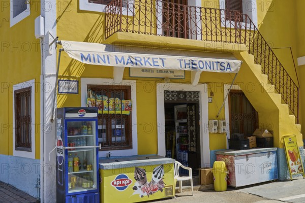 Yellow building with mini market and advertising signs, surrounded by summer flair, Kattavia village, southern tip of Rhodes, Rhodes, Dodecanese, Greek Islands, Greece
