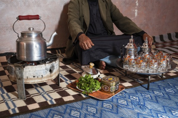 Moroccan man in front of the tea set with the kettle and glasses
