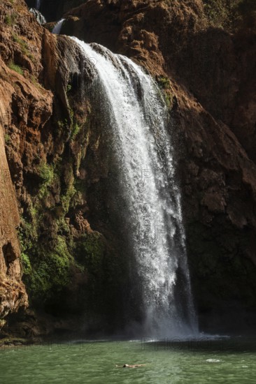 Relaxed woman floats on his back under beautiful Ouzoud waterffall in Morocco