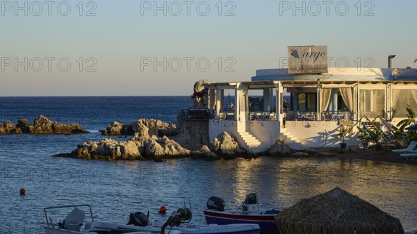 Restaurant Argo, evening mood at a restaurant with sea view and small boats in front of rocky coast, bay, Charaki, Haraki, east coast Rhodes, Rhodes, Dodecanese, Greek Islands, Greece