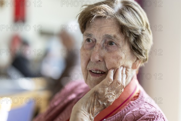 Close-up, authentic, unposed portrait of a 90+ year old senior woman with dementia and Alzheimer's disease in a retirement home, holding a hand to her face, Cologne, North Rhine-Westphalia, Germany