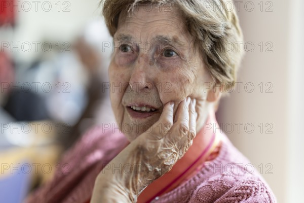 Close-up, authentic, unposed portrait of a 90+ year old senior woman with dementia and Alzheimer's disease in a retirement home, holding a hand to her face, Cologne, North Rhine-Westphalia, Germany