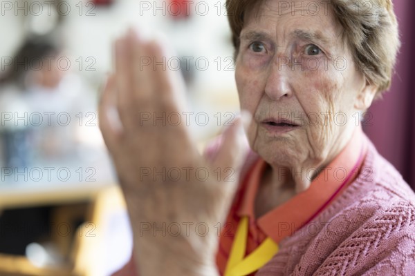 Over 90-year-old senior citizen with dementia talks and gesticulates with her wrinkled hands in a retirement home, Cologne, North Rhine-Westphalia, Germany