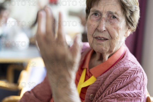 Over 90-year-old senior citizen with dementia talks and gesticulates with her wrinkled hands in a retirement home, Cologne, North Rhine-Westphalia, Germany