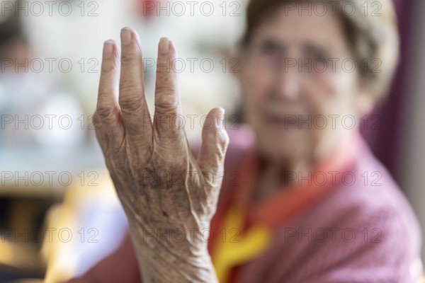 Over 90-year-old senior citizen with dementia talks and gesticulates with her wrinkled hands in a retirement home, Cologne, North Rhine-Westphalia, Germany