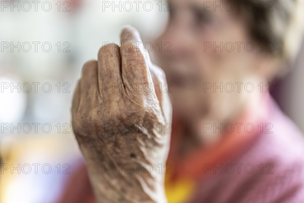 Over 90-year-old senior citizen with dementia talks and gesticulates with her wrinkled hands in a retirement home, Cologne, North Rhine-Westphalia, Germany