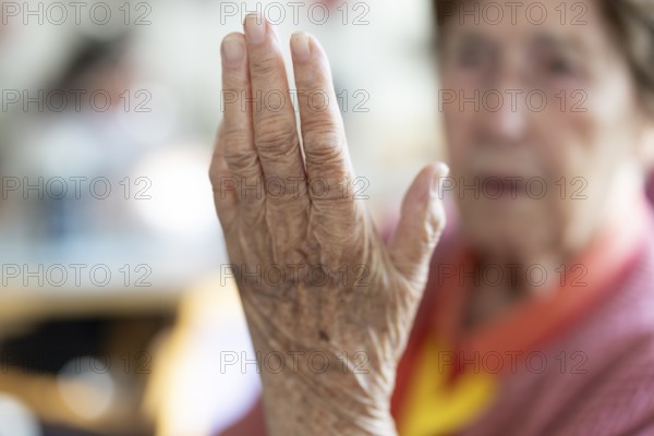 Over 90-year-old senior citizen with dementia talks and gesticulates with her wrinkled hands in a retirement home, Cologne, North Rhine-Westphalia, Germany