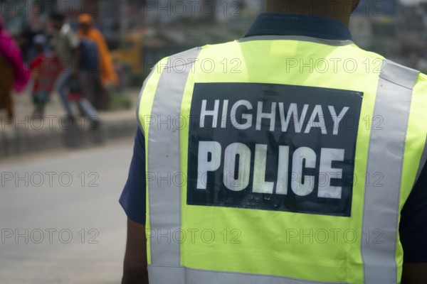 Highway police officer on duty viewed from the back with a reflective vest, Dhaka, Bangladesh