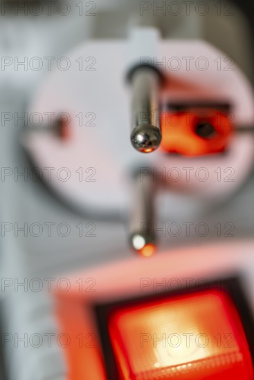 Close-up of a white power plug, Schuko plug, on a multiple socket with red indicator light, symbolic image for electricity, electrical energy, power consumption, studio shot, Germany