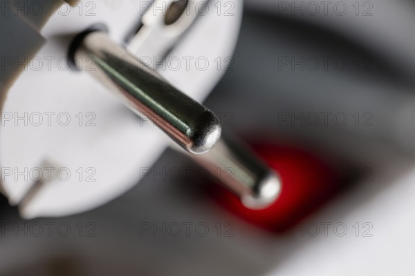 Close-up of a white power plug, Schuko plug, on a multiple socket with red indicator light, symbolic image for electricity, electrical energy, power consumption, studio shot, Germany
