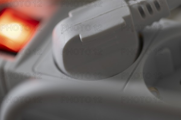 Close-up of a white power plug, Schuko plug, plugged into a multiple socket with red indicator light, symbolic image for electricity, electrical energy, power consumption, studio shot, Germany