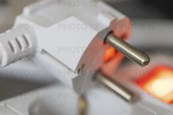 Close-up of a white power plug, Schuko plug, on a multiple socket with red indicator light, symbolic image for electricity, electrical energy, power consumption, studio shot, Germany