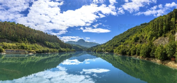 The serene ibiur reservoir mirrors the sky and surrounding hills, creating a tranquil panorama of nature's beauty in the heart of gipuzkoa, basque country