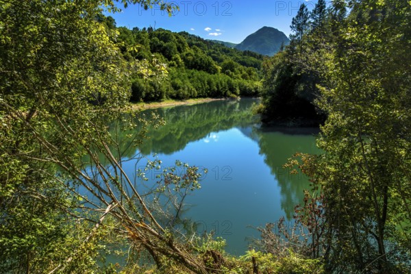 Ibiur reservoir is reflecting the surrounding lush vegetation and blue sky on a beautiful sunny day near tolosa, in gipuzkoa, basque country