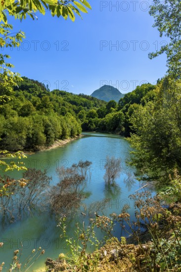 Ibiur reservoir reflecting vibrant trees and a majestic mountain adorned with lush vegetation on a sunny summer day in tolosa, gipuzkoa, basque country, spain