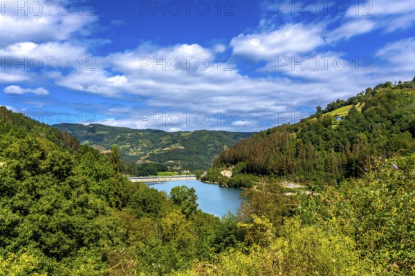 Serene ibiur reservoir nestled among lush hills of tolosa in the basque country, featuring a vibrant blue sky and fluffy white clouds, embodies natural tranquility