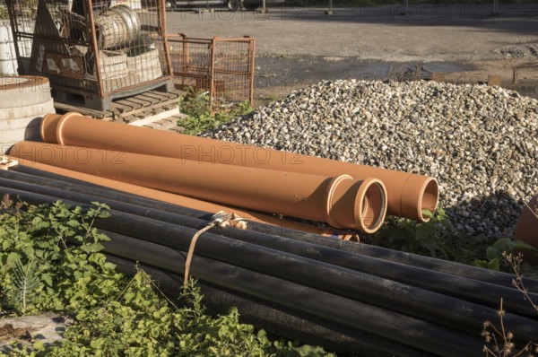 Borken, NRW, Germany, Orange and black plastic pipes are lying on a construction site, waiting to be installed