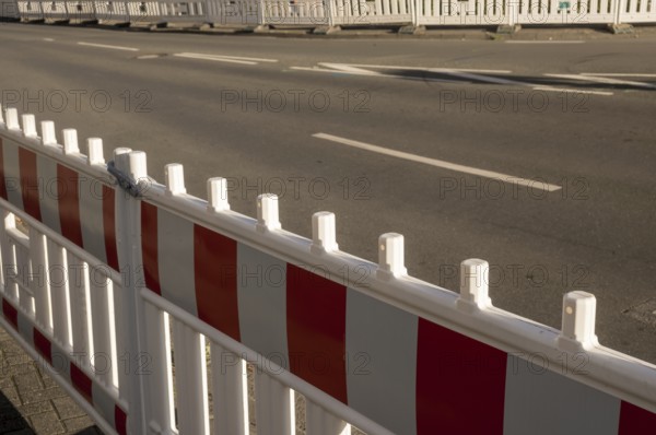 Borken, NRW, Germany, Red and white striped plastic construction barrier closing an empty asphalt street during roadworks