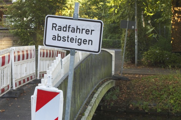 Borken, NRW, Germany, Cyclists dismount sign and construction barriers blocking access to a small bridge over a canal in germany