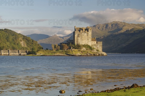 A picturesque castle on an island in the water, surrounded by mountains and a slightly cloudy sky, with dramatic mountains in the background, Eilean Donan Castle, Highlander, film set, Scotland, Great Britain