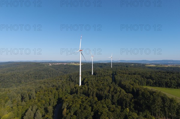 Wind turbines above green forests under a blue sky, symbolising clean energy, near Schorndorf in Remstal, Baden-Württemberg, Germany