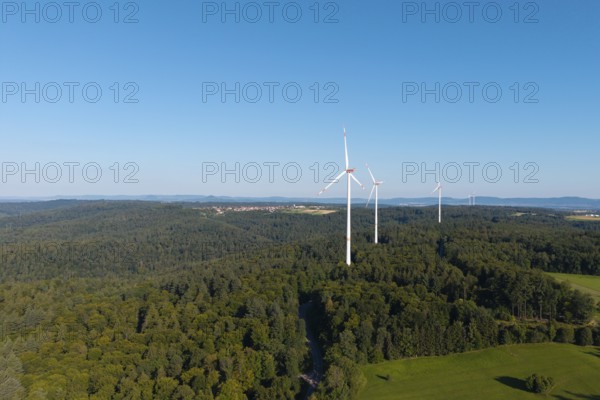 Three wind turbines rise above lush forest and green countryside, near Schorndorf, Rems Valley, Baden-Württemberg, Germany