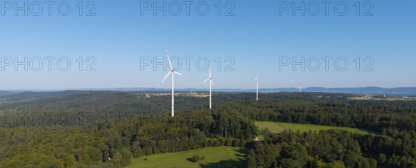 Wind turbines stand above a wooded hill under a clear blue sky, near Schorndorf, Rems Valley, Baden-Württemberg, Germany