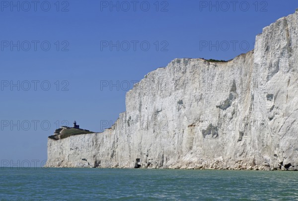 Wide cliff landscape with a small lighthouse under a blue sky. Old Harrys Rock, Bournemouth, Dorset, England, Great Britain