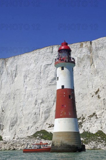 Red lighthouse and boat near white cliffs by the sea, Beachy Head Lighthouse, Bournemouth, Dorset, England, Great Britain
