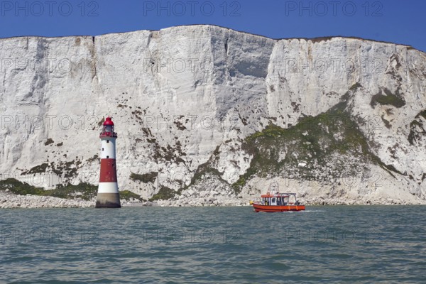 Red lighthouse and boat near white cliffs by the sea, Beachy Head Lighthouse, Bournemouth, Dorset, England, Great Britain