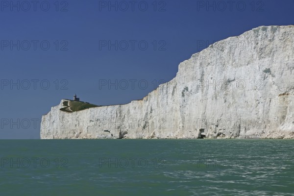 White cliffs with a small lighthouse by the turquoise sea, Old Harrys Rock, Bournemouth, Dorset, England, Great Britain
