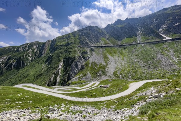 View from elevated position on serpentine hairpin bends of southern ramp southern ascent descent in southern part of old historic St. Gotthard pass road Tremola Gotthardpass Alpine pass mountain road with cobblestones, in the background above new pass road with gallery for protection against rockfall and snow, Swiss Alps, Airolo, Canton Ticino, Ticino, Switzerland