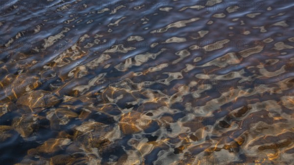 Light reflections on a wavy water surface, forest lake, Norway