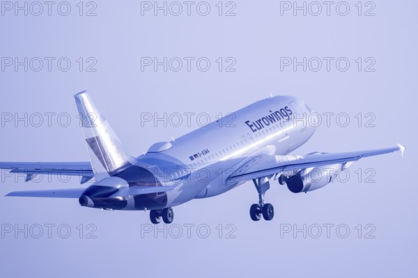 A Eurowings aeroplane takes off into the sky in blue light, Stuttgart, Baden-Württembwerg, Germany