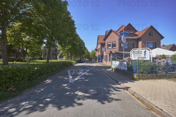 Restaurant Zum alten Pauker, clinker brick building, general development, historic cemetery, trees, lawn, road, road marking Attention children, blue sky, cloudless, Alte Schulstraße, Alfhausen, district of Osnabrück, Lower Saxony, Germany