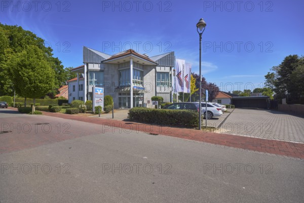 Vereinigte Volksbank eG - Branch Alfhausen, modern architecture, lantern, car park with vehicles, trees, hedges, blue sky, cirrostratus clouds, main street, Alfhausen, district of Osnabrück, Lower Saxony, Germany