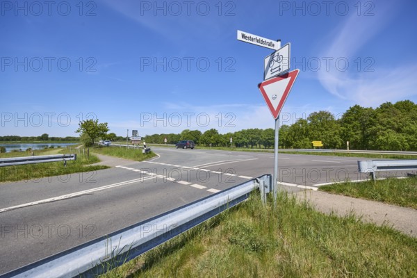 Landscape, roads, footpath and cycle path, crash barrier, traffic signs, give way, additional sign for cyclists crossing, trees, grass, blue sky, cirrostratus clouds, intersection of Riester Straße and Westerfeldstraße, Alfhausen, Osnabrück district, Lower Saxony, Germany